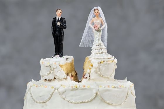 Wedding cake with a split between plastic bride and groom on top of cake