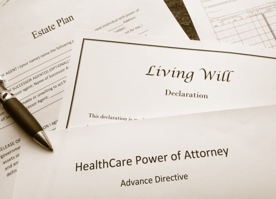 Legal documents laying on a table, including a Living Will Declaration, an Estate Plan, and a HealthCare Power of Attorney Advance Directive