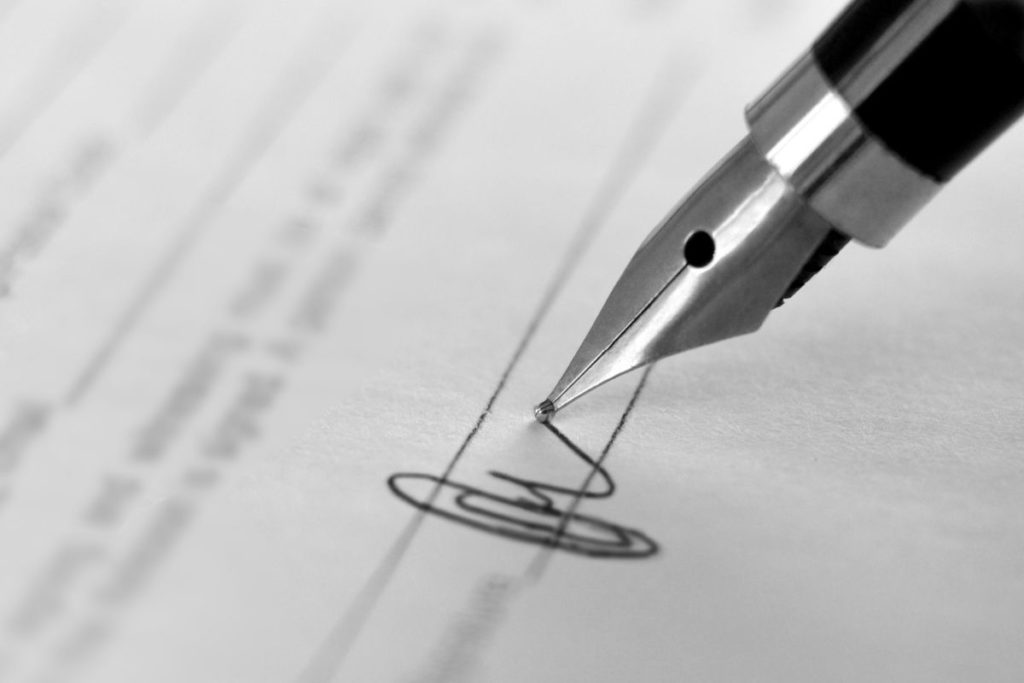 Close up of an ink pen being used to sign a document.